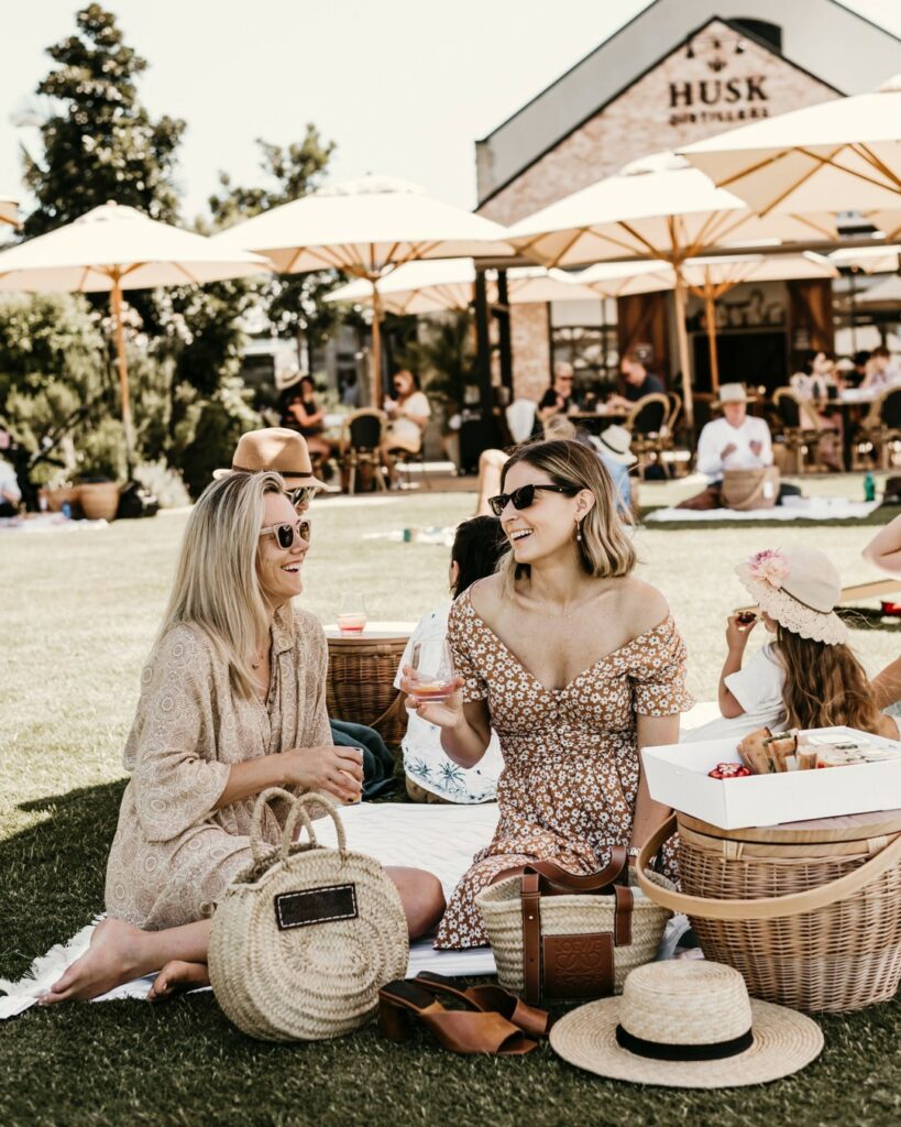 Two ladies sitting on the lawn having a cocktail at husk