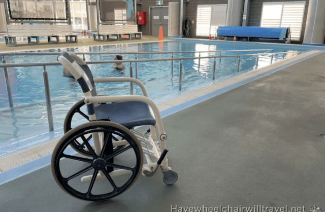 Featuring a wheelchair by the poolside and someone enjoying a swim, embodying accessibility and enjoyment