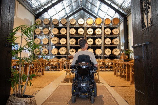 Man in electric wheelchair in Husk Farm Distillery barrel room