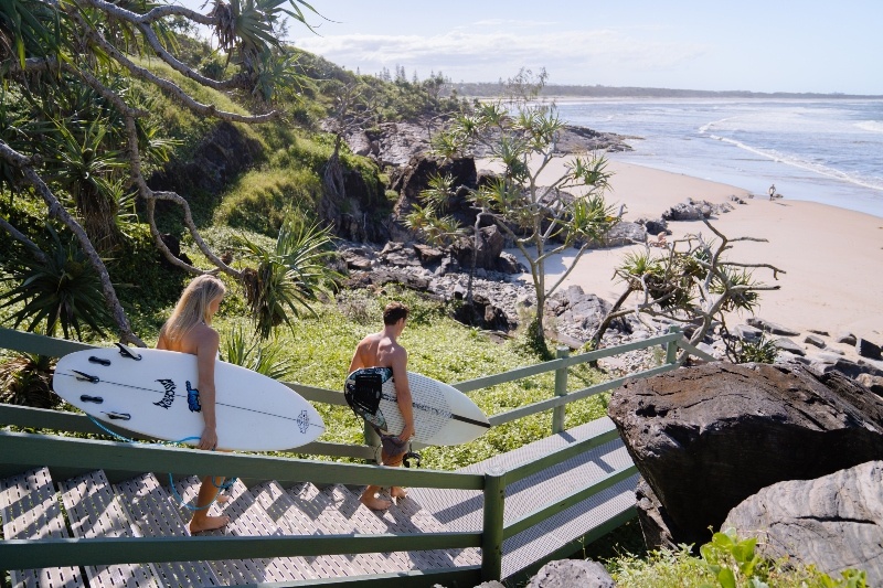 couple walking surfboards down to cabarita beach